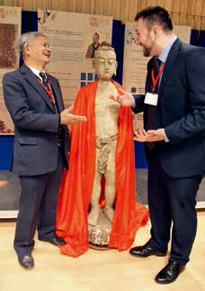 November 18, 2018: At Cambridge University, Philip Rose-Neil (right), member of the Governing Board of the British Acupuncture Council, and Ma Boying, chairman of the Federation of Traditional Chinese Medicine in the UK, talk near an ancient wooden dummy used for practicing acupuncture. A campaign was held there to promote communication on traditional Chinese medicine and acupuncture along the Belt and Road routes. VCG