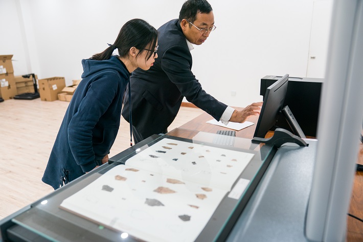 Liu Yongge (right) instructs his student to scan oracle bone inscriptions and put them into the big data platform. At present, the platform has collected 246 oracle bone script catalogs and published 46 of them.  by Xu Xun